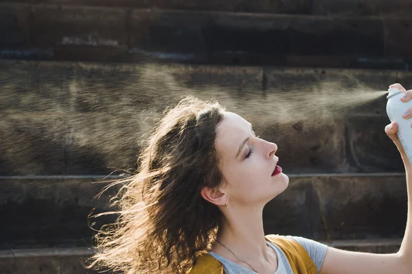 Mladá žena osvěžující tvář s termální vodou. Těší, péče o pleť, vlny veder koncept. — Stock fotografie