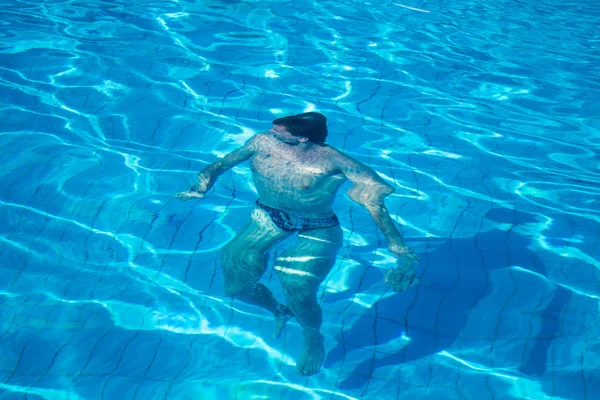 Человек плавает под голубой водой — стоковое фото