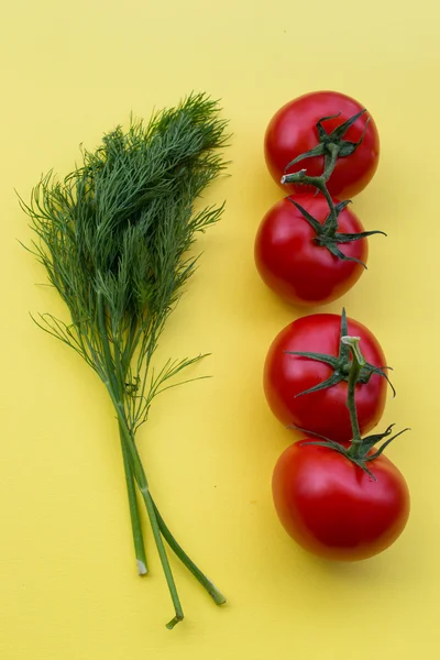 Dill and four tomatoes on yellow background, vertical — Stock Photo, Image