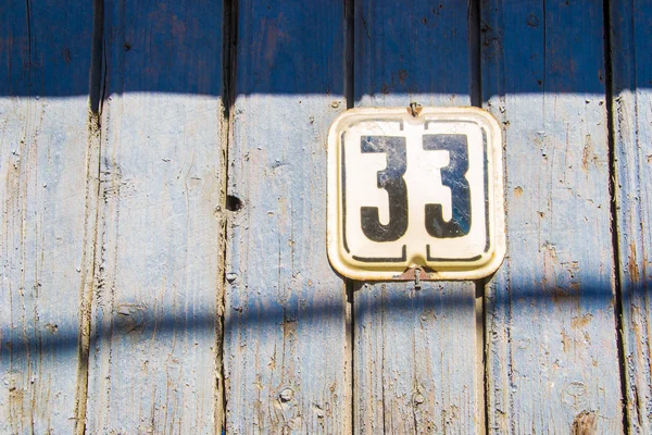 Nummer 33 auf der hölzernen, blau rissigen Wand — Stockfoto