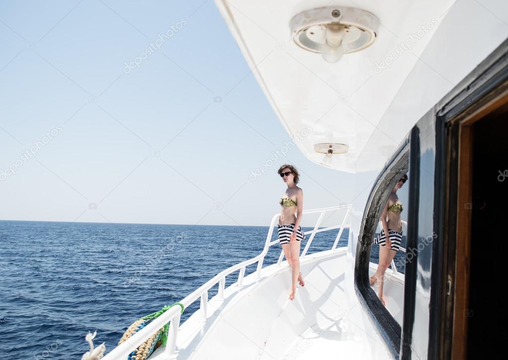 Beautiful young woman in sun glasses on yacht, open sea