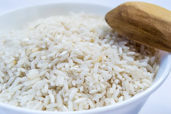 raw long rice in white plate and wooden spoon,