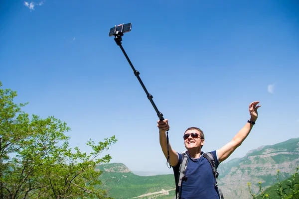 A fiatalember kezedet monopod, figyelembe selfie a mobiltelefon — Stock Fotó