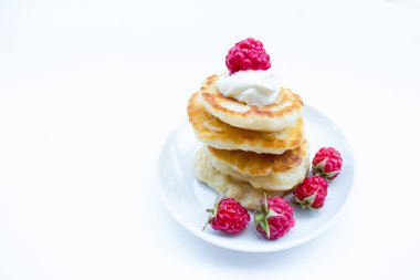 Stack of pancakes on plate  raspberries and sour cream, isolated