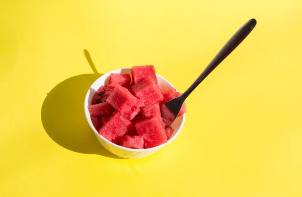 Pieces watermelon in bowl with fork, yellow background — Stock Photo, Image