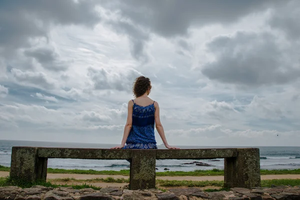 Deniz kenarında bankta oturan kadın — Stok fotoğraf