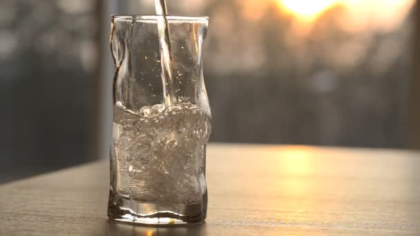 El agua limpia se vierte en un vaso al atardecer — Vídeos de Stock