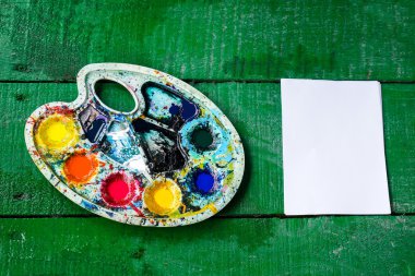 Yeşil bir ahşap masa temiz levha ve renkli palet. Üstten Görünüm