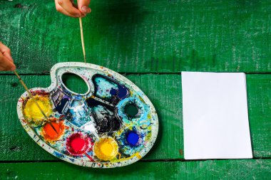 Çocuk yığınları ile elleri. Su üzerinde boya. Renk paleti ve temiz bir sayfayla