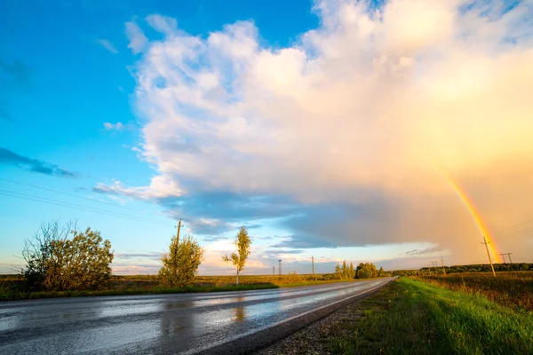 Landscape with country road and rainbow — Stock Photo, Image