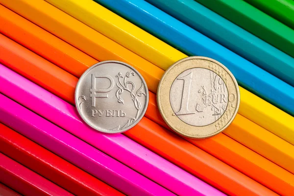 Монеты на цветных карандашах — стоковое фото