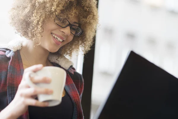 Girl gazdaság egy csésze, miközben dolgozik a laptop — Stock Fotó