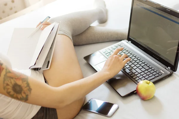 Tjej som arbetar på sin laptop i sängen — Stockfoto