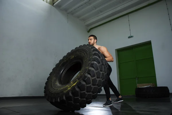 Bodybuilder kippt Reifen im Fitnessstudio — Stockfoto