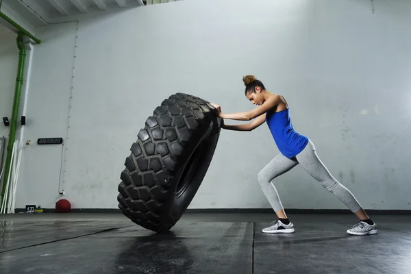 Femme flipping pneu à la salle de gym — Photo