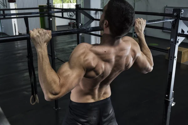 Bodybuilder doen van pull ups op de sportschool — Stockfoto