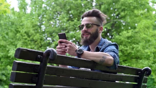 Modeste sitzt auf der Bank im Park — Stockvideo