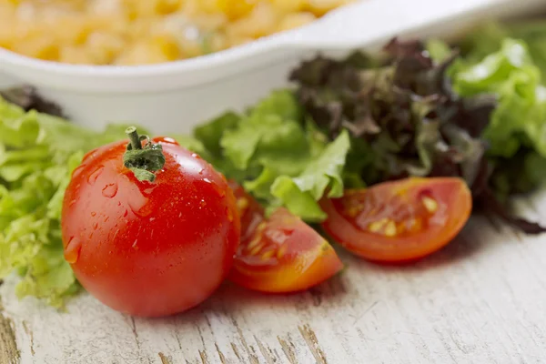 Verse cherry tomaten naast onverpakt chicken tortilla op houten tafel — Stockfoto