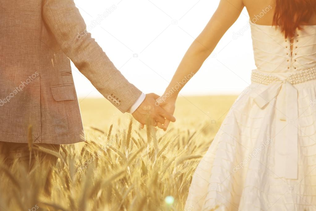 Wedding couple holding hands in field of rye