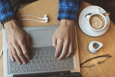 Kafede dizüstü bilgisayarda çalışan genç hipster adam