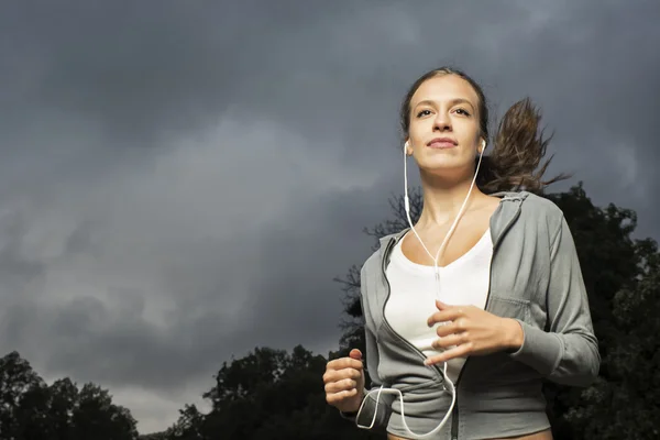 Aantrekkelijk meisje joggen in het park voor storm — Stockfoto