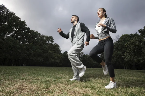 Atractiva pareja joven corriendo en el parque — Foto de Stock