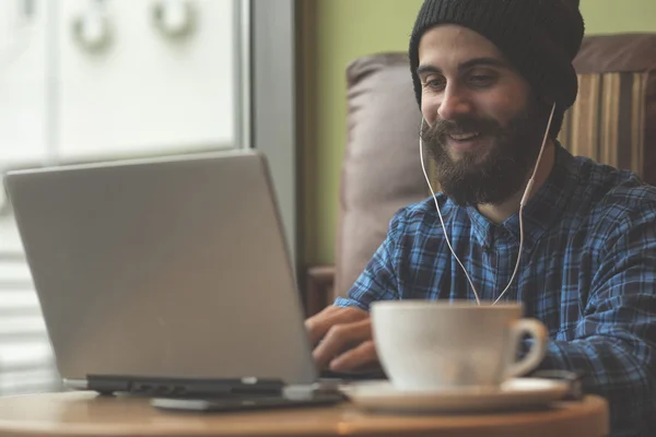 Pemuda hipster bekerja pada laptop di warung kopi — Stok Foto