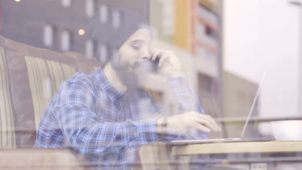 Joven hombre de moda hipster trabajando en el ordenador portátil en la cafetería — Vídeos de Stock