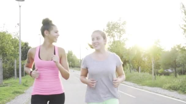 Two young girl jogging together in the park — Stock Video