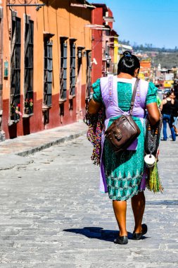 Geleneksel kıyafetler giymiş bir kadın Meksika 'daki bir sömürge kasabasında kaldırım taşı caddesinde yürüyor.