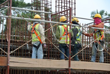 İnşaat İşçileri şantiyede beton duvar için çelik takviye imal.
