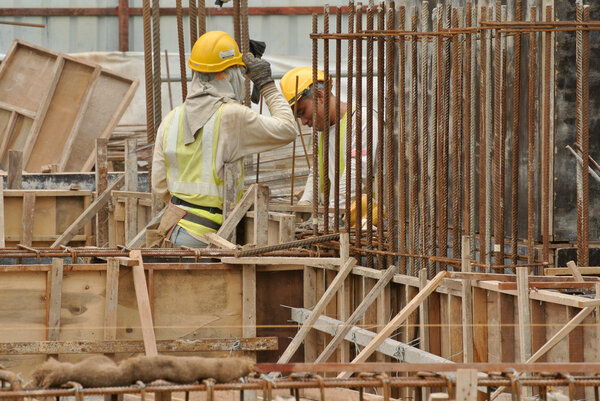 Two construction workers fabricating ground beam steel reinforcement bar