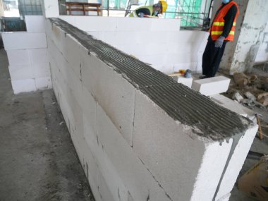 SEREMBAN, MALAYSIA - 16 Mart 2020: İnşaat işçileri inşaat alanında otoklasik beton blok döşüyorlar. Bu materyalin kullanımı zaman kazandırabilir ve inşaat işini kolaylaştırabilir.