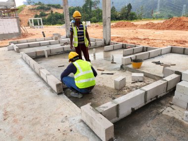 SEREMBAN, MALAYSIA - 16 Mart 2020: İnşaat işçileri inşaat alanında otoklasik beton blok döşüyorlar. Bu materyalin kullanımı zaman kazandırabilir ve inşaat işini kolaylaştırabilir.