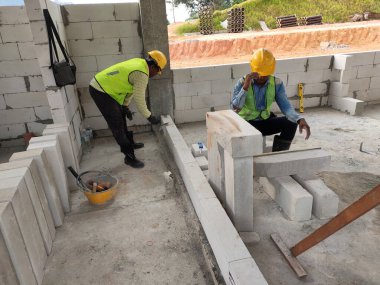 SEREMBAN, MALAYSIA - 16 Mart 2020: İnşaat işçileri inşaat alanında otoklasik beton blok döşüyorlar. Bu materyalin kullanımı zaman kazandırabilir ve inşaat işini kolaylaştırabilir.