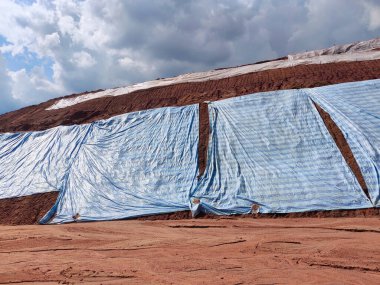 SEREMBAN, MALASIA - 4 Mart 2020: Plastik tabaka erozyonu önlemek için yamacın yüzeyine yayıldı. Ayrıca geçici olarak dengeleme işlemi bitmeden önce eğimi sabitlemek için..