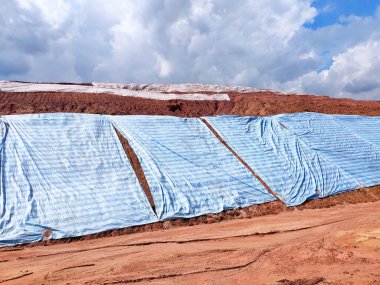 SEREMBAN, MALASIA - 4 Mart 2020: Plastik tabaka erozyonu önlemek için yamacın yüzeyine yayıldı. Ayrıca geçici olarak dengeleme işlemi bitmeden önce eğimi sabitlemek için..