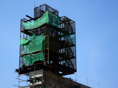 SHAH ALAM, MALAYSIA -6 AĞUSTOS 2020: Yüksek beton sütunların yapımında geçici merdiven ve iskeleler kullanılır. İskele, güvenlik amaçlı güvenlik ağlarıyla sarılı. İşçiler tarafından kurulmuş. 