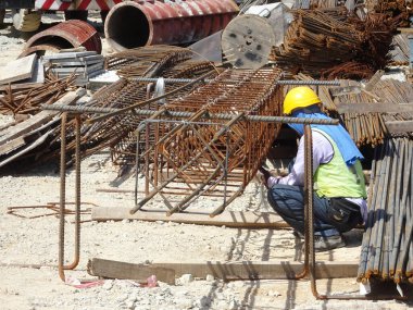 SHAH ALAM, MALAYSIA - 23 Mart 2020: İnşaat işçileri inşaat alanında çelik takviye çubuğu üretiyorlar. Kereste kalıplarını kullanarak kaplamadan önce ince telleri kullanarak birbirlerine bağladılar..