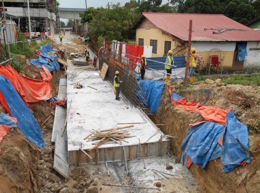 SHAH ALAM, MALAYSIA - 23 Mart 2020: İnşaat işçileri inşaat alanında çelik takviye çubuğu üretiyorlar. Kereste kalıplarını kullanarak kaplamadan önce ince telleri kullanarak birbirlerine bağladılar..