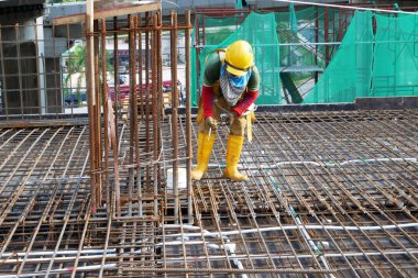 SHAH ALAM, MALAYSIA - 23 Mart 2020: İnşaat işçileri inşaat alanında çelik takviye çubuğu üretiyorlar. Kereste kalıplarını kullanarak kaplamadan önce ince telleri kullanarak birbirlerine bağladılar..