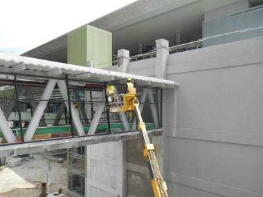 SELANGOR, MALAYSIA - 16 Şubat 2017: İnşaat işçileri inşaat alanında yüksek seviyede çalışırken taşınabilir vinç kovası kullanıyorlar. İşçiler tarafından kontrol edilen kova hareketi..  