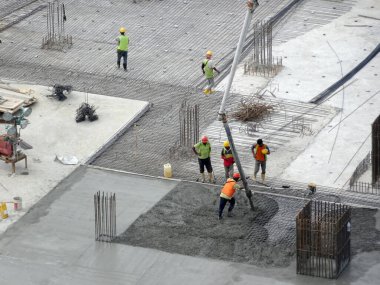 JOHOR, MALAYSIA - Mart 04, 2017: İnşaat işçileri inşaat sahasındaki beton pompalama makinesinin beton hortumunu kullanarak ıslak beton dökerek inşaat sahasındaki döşeme döşeme düzenine döküyorlar.  
