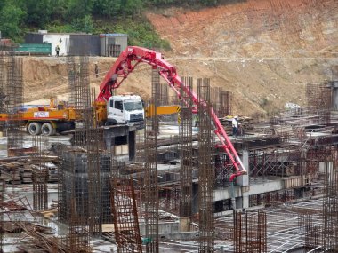 JOHOR, MALAYSIA - Mart 04, 2017: İnşaat işçileri inşaat sahasındaki beton pompalama makinesinin beton hortumunu kullanarak ıslak beton dökerek inşaat sahasındaki döşeme döşeme düzenine döküyorlar.  