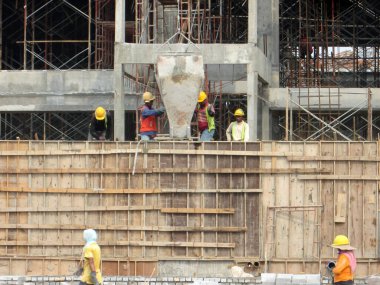 MALACCA, MALAYSIA - 09 Mart 2017: İnşaat işçileri, vinçle taşınan beton kovayla ıslak beton dökerek inşaat alanındaki kereste biçimine döküyorlar.. 