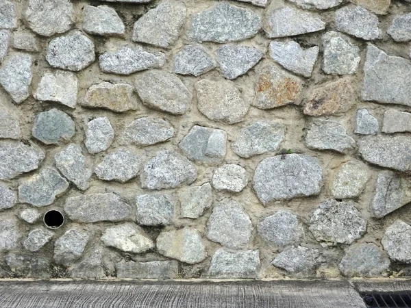 Stone rubble wall. Used as retaining wall. The stone bond together using cement mortar and adhesive.