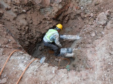 SELANGOR, MALAYSIA - 25 Mayıs 2015: Kazılmış siperlerin içinde çalışan inşaat işçileri. Yararlı boruları kur ve onar. 
