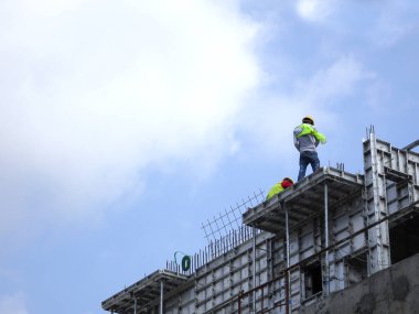 KANGAR, MALAYSIA - 31 Temmuz 2017: Vücut koşum takımı gibi düzgün güvenlik teçhizatı giymeden yükseklerde çalışan inşaat işçileri. Bu tehlikeli hareket kazalara ve ölümlere neden olabilir..