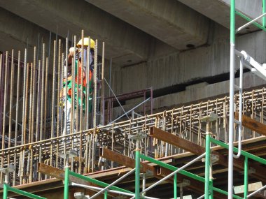 MALACCA, MALAYSIA - 2 Mart 2020: İnşaat işçileri inşaat alanında yükseklik takviye çubukları kurun. Onlara koşum takımı ve diğer güvenlik ekipmanları sağlanıyor..