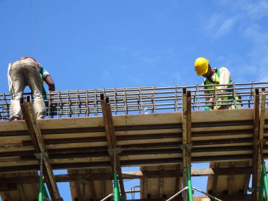 MALACCA, MALAYSIA - 2 Mart 2020: İnşaat işçileri inşaat alanında yükseklik takviye çubukları kurun. Onlara koşum takımı ve diğer güvenlik ekipmanları sağlanıyor..